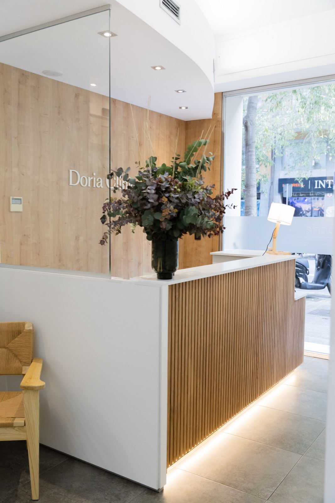 Recepción de Doria Clinic, con mostrador de madera y el logo en la pared